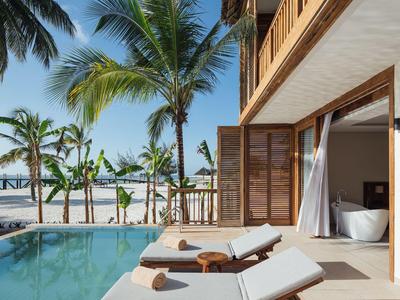 Basen z leżakami z widokiem na palmy i morze z pokoju hotelowego z otwartym balkonem.