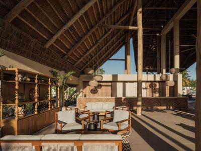 Otwarta przestrzeń lounge z drewnianymi meblami, dachem ze słomy i widokiem w tropikalnym hotelu.