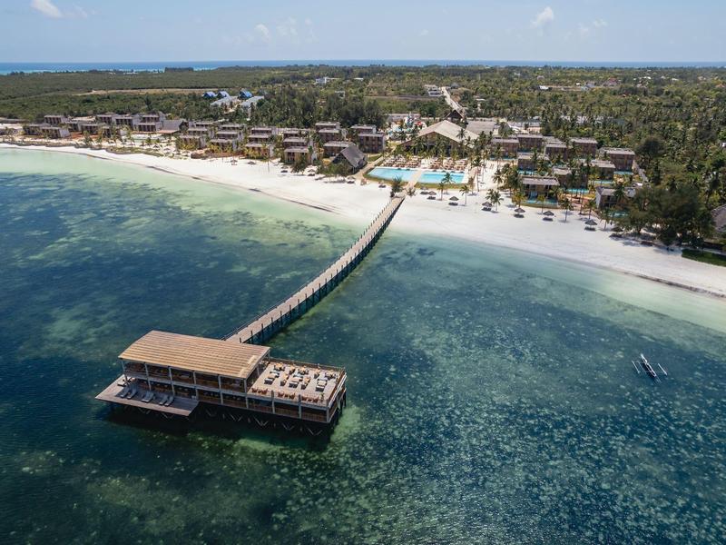 Vista di un resort sulla spiaggia con un lungo molo sull'acqua limpida.