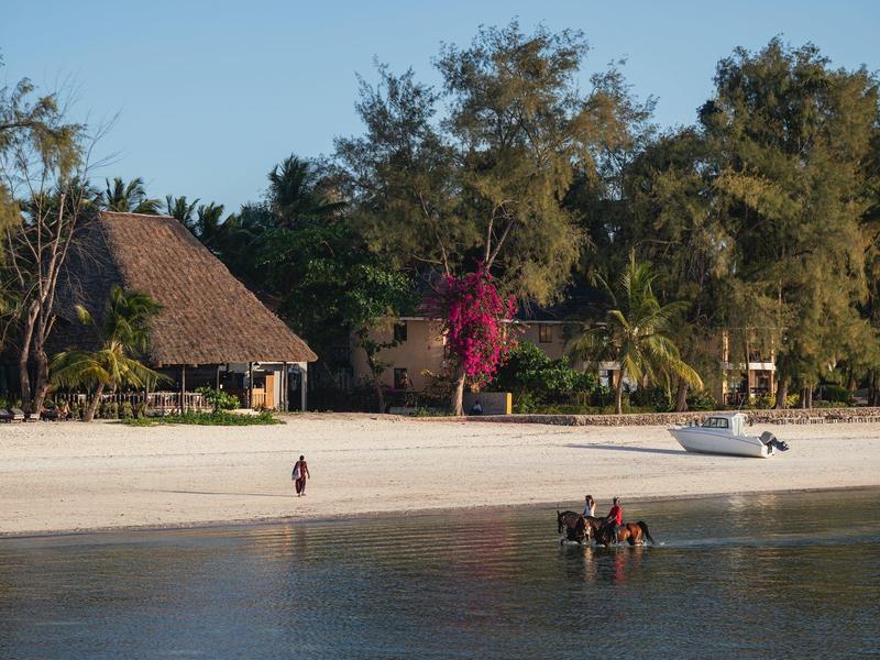 Spiaggia con palme, una capanna con tetto di paglia e una piccola barca vicino all'acqua calma