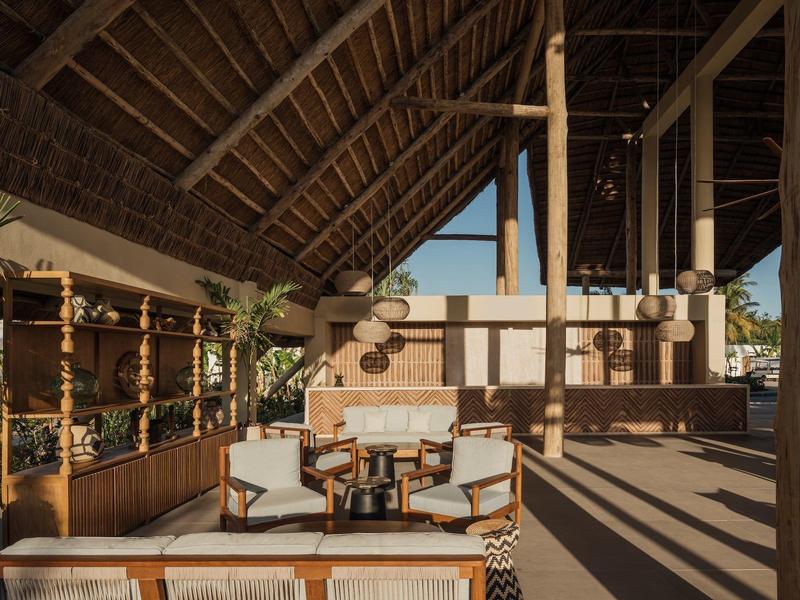 Area lobby aperta dell'hotel con mobili in legno e vista sul mare.