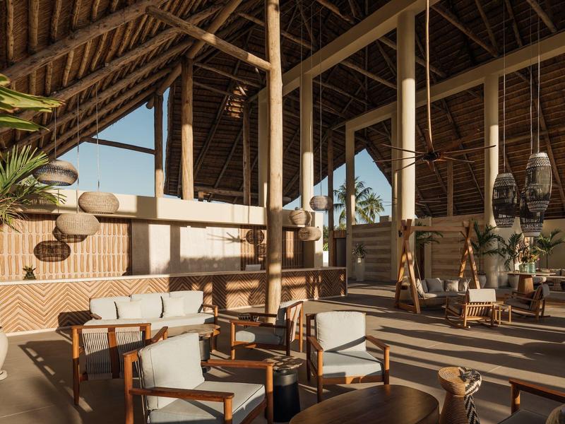 Ampio soggiorno luminoso con mobili in legno e soffitti alti in bambù in un hotel tropicale