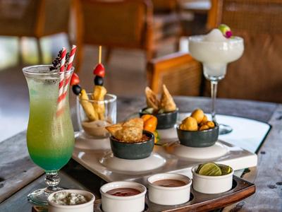 Verschiedene Drinks und Snacks auf einem Holztisch in einem gemütlichen Innenraum.