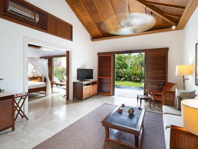 Modern eingerichtetes Wohnzimmer mit Holzmöbeln, hoher Holzdecke und Blick auf einen Garten.