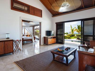 Helles Wohnzimmer mit Holzmöbeln, Kontrast zwischen weißen Wänden und dunklen Türen, Blick auf Garten.