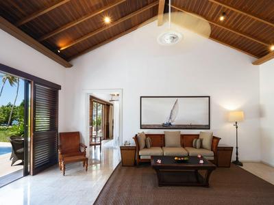 Helles Wohnzimmer mit Holzbalkendecke, braunem Sofa, großem Fenster und offenem Zugang zum Garten.