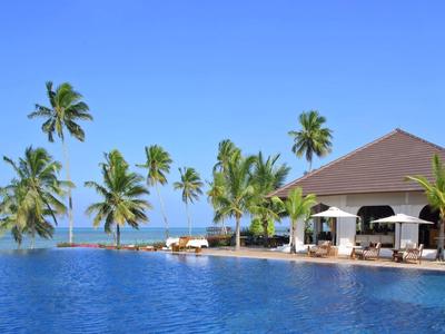 Infinity-Pool mit Palmen und einer offenen Strandbar unter blauem Himmel am Meer.