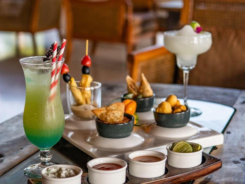 Verschiedene Drinks und Snacks auf einem Holztisch in einem gemütlichen Innenraum.