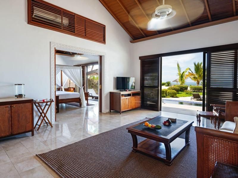 Helles Wohnzimmer mit Holzmöbeln, Kontrast zwischen weißen Wänden und dunklen Türen, Blick auf Garten.