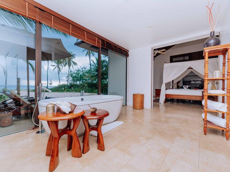 Moderner Raum mit freistehender Badewanne, Holzmöbeln und großer Glaswand mit Gartenblick.