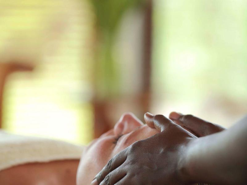 Eine Person erhält eine sanfte Kopfmassage, Hintergrund hell und unscharf.