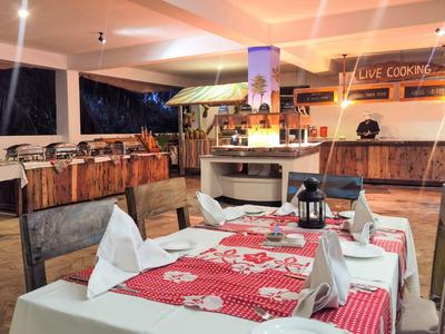 Ein gedeckter Esstisch mit rot-weiß kariertem Läufer in einem rustikalen überdachten Außenbereich.