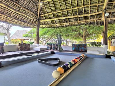 Buiten biljarttafel onder rieten dak met zitplaatsen en groene omgeving.