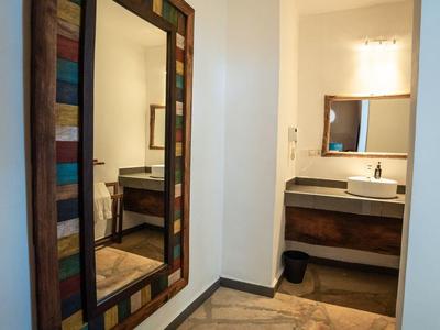 Moderner Waschbereich mit Waschtisch, Spiegel und Farbspiegel im Flur mit Holzboden.