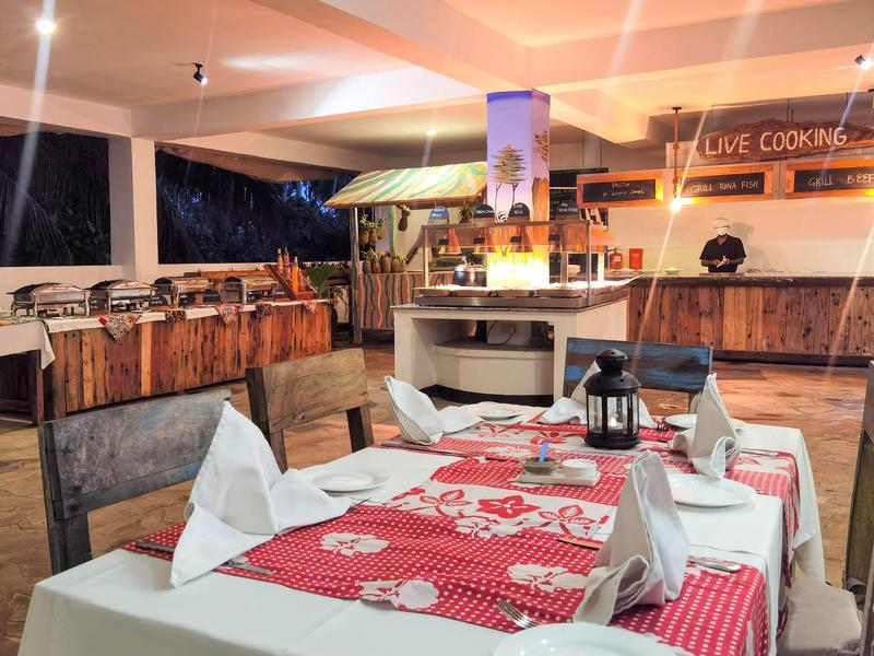 Ein gedeckter Esstisch mit rot-weiß kariertem Läufer in einem rustikalen überdachten Außenbereich.