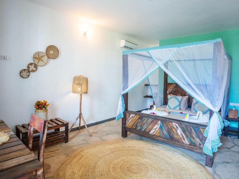 Helles Schlafzimmer mit Baldachinbett, Holzmöbeln, Teppich und Stehlampe im Landhausstil.