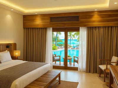 Modernes Hotelzimmer mit Bett, Holzmöbeln und Blick auf einen Pool durch die Balkontür.