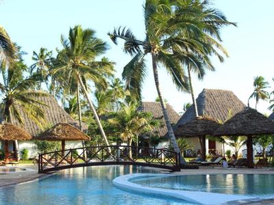 Poolbereich mit Palmen und Strohdachhütten in tropischem Resort