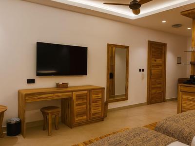 Camera d'hotel moderna con mobili in legno, TV a muro e grande specchio.