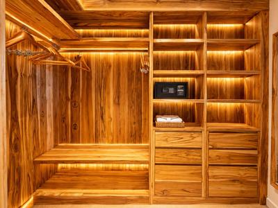 Grand dressing en bois clair avec étagères, tiroirs et coffre-fort.