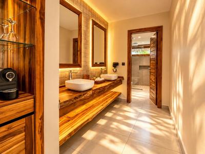 Salle de bain lumineuse avec meuble en bois, deux lavabos et grands miroirs.
