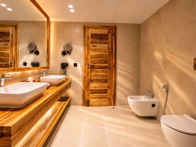 Salle de bain moderne avec comptoirs en bois, doubles lavabos et équipements sanitaires blancs.