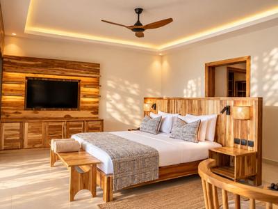 Chambre d'hôtel moderne avec lit double, meubles en bois et éclairage chaleureux.