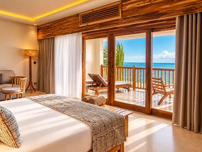 Chambre d'hôtel lumineuse avec lit double et vue sur terrasse avec vue mer.