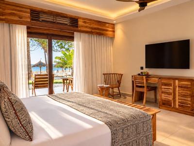 Chambre d'hôtel lumineuse avec lit double, mobilier en bois et balcon avec vue sur la mer.