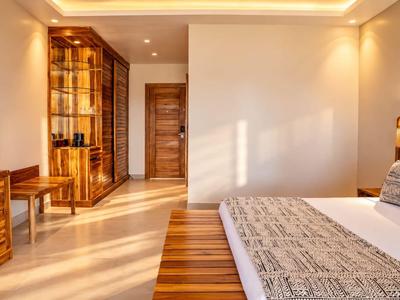 Chambre d'hôtel lumineuse avec mobilier en bois et grand lit double avec linge de lit à motifs.