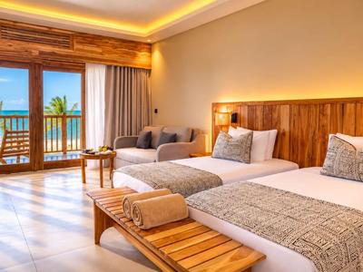 Chambre d'hôtel avec deux lits, mobilier en bois et balcon avec vue sur la mer.
