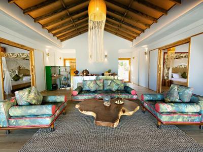 Prostorný obývací pokoj s tyrkysovými pohovkami, velkým závěsným světlem a teplou, vstřícnou atmosférou.