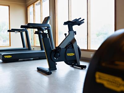 Fitness místnost s běžeckým pásem a rotopedem před velkými okny hotelu.