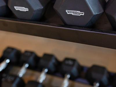 Černé šestistranné činky na dvoupatrovém stojanu v posilovně.