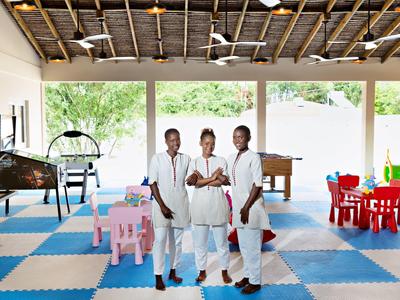 Tři zaměstnanci v uniformách stojí v dětské herně s barevnými hračkami.