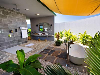 Hotelová terasa s venkovní vanou, zelenými rostlinami a žlutým slunečníkem.