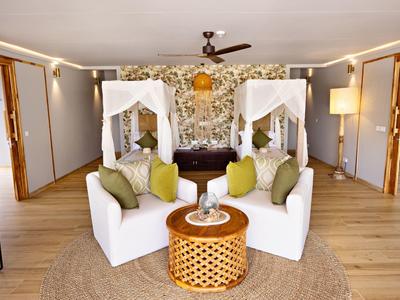 Elegantní hotelový salonek s bílými pohovkami, dřevěným stolem a květinovou výzdobou.