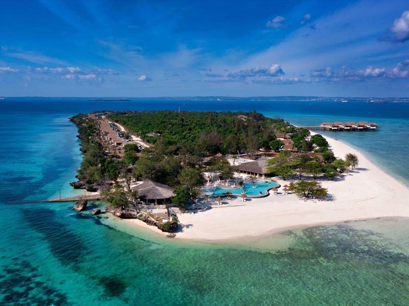 Tropický ostrov s bílými plážemi, tyrkysovým mořem a resortem s bazény.