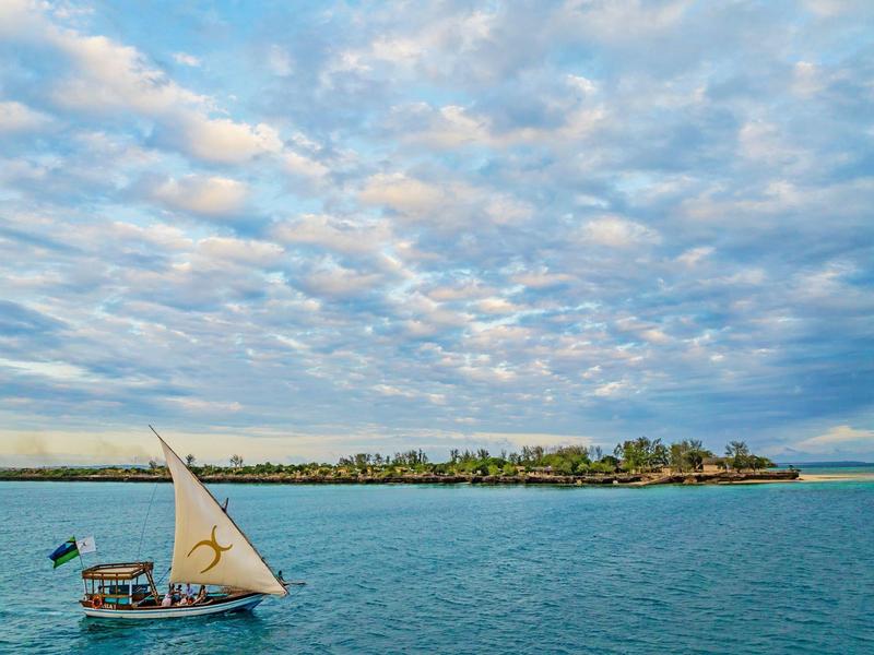 Tropický ostrov s tradiční plachetnicí na klidném modrém moři.