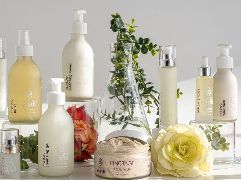 Elegantní kosmetické produkty s čerstvými květinami na světlém bílém povrchu.