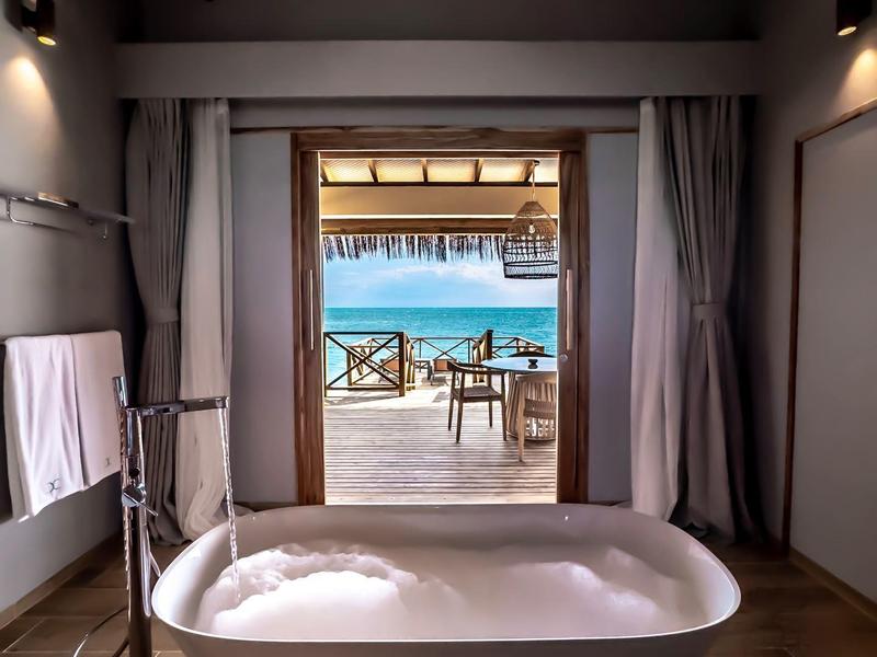 Volně stojící vana s výhledem na terasu a moře.