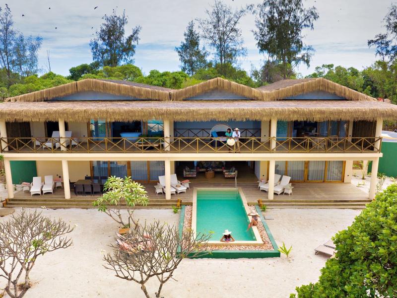 Velká moderní vila s bazénem obklopená bujnou vegetací.