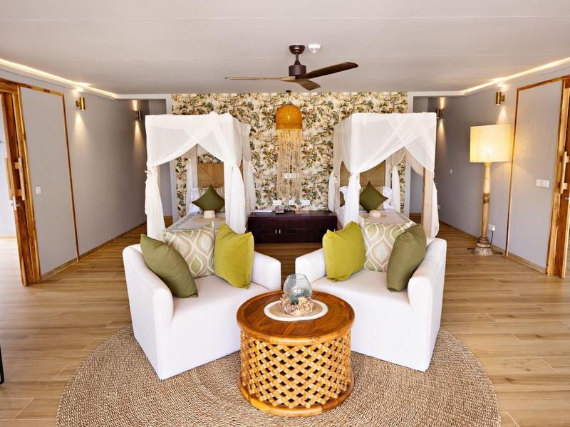 Elegantní hotelový salonek s bílými pohovkami, dřevěným stolem a květinovou výzdobou.