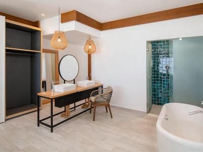 Modern bathroom with double sinks, wooden accents, and a freestanding bathtub.