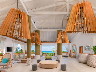 Světý, otevřený hotelový lobby interiér se stylovými dřevěnými lampami a výhledem na moře.