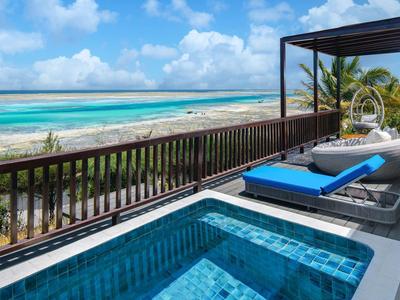 Terrace with pool, sun loungers, and ocean view under clear skies.