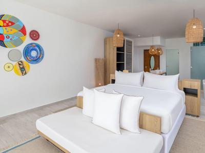Modern hotel room with white bedding and colorful wall decorations.