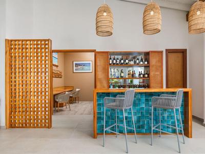Modern hotel bar area with turquoise mosaic and bamboo lamps.