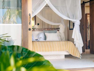 Gemütliches Schlafzimmer mit Himmelbett und weißen Vorhängen, moderner Einrichtung und Pflanzenblick.