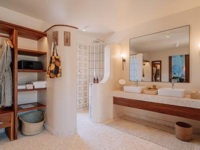 Helles Badezimmer mit Doppelwaschbecken, großem Spiegel und offenem Kleiderschrank aus Holz.